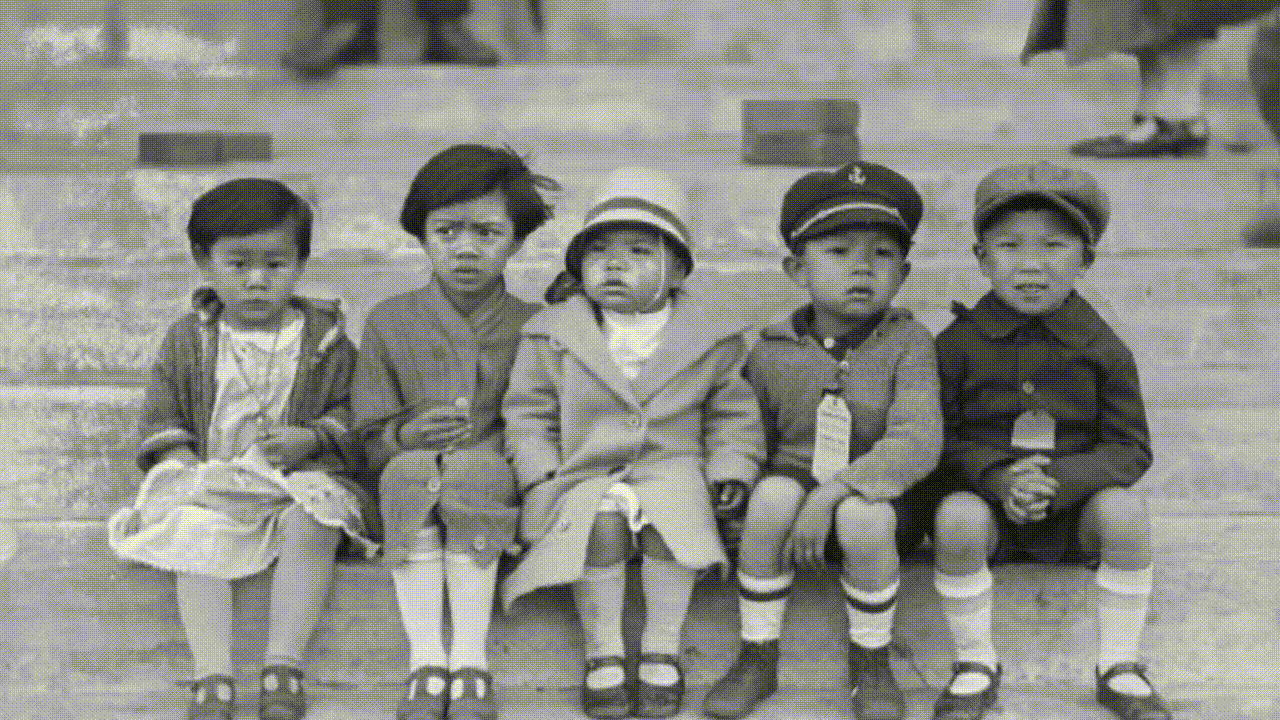 Several Chinese Canadian school children sit on the ground